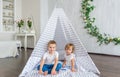 Cute happy little children sitting in teepee at nursery.