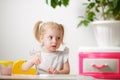 Cute happy little girl, adorable preschooler, painting with water color situng in a sunny white room at home or elementary school Royalty Free Stock Photo