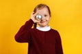 Cute happy little girl with christmas ball toy. Closeup child in a vinous sweater on a yellow background