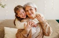 Cute happy little girl granddaughter hugging delighted elderly grandmother during Christmas holidays Royalty Free Stock Photo