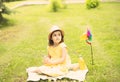 Cute happy little girl in a hat having fun in park meadow. Child sitting on a blanket. Picnic on nature Royalty Free Stock Photo