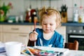 Cute happy little girl painting with water color on paper. Baby child learning different skills, creative leisure and Royalty Free Stock Photo