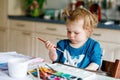 Cute happy little girl painting with water color on paper. Baby child learning different skills, creative leisure and Royalty Free Stock Photo