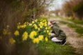 Cute happy little girl in the spring country smelling yellow daffodils Royalty Free Stock Photo