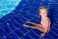 Cute happy little girl in the swimming pool looks Royalty Free Stock Photo