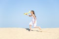 Cute happy little girl wearing a white dress running on the sandy beach by the sea and playing with the yello Royalty Free Stock Photo