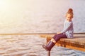 Cute happy little smiling child girl in rubber boots fishing from wooden pier on a lake. Family leisure activity during summer Royalty Free Stock Photo