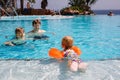 Cute happy little toddler girl, school kid boy and father in the pool and having fun on family vacations in a hotel Royalty Free Stock Photo