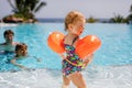 Cute happy little toddler girl, school kid boy and father in the pool and having fun on family vacations in a hotel Royalty Free Stock Photo