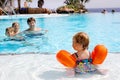 Cute happy little toddler girl swimming in the pool and having fun on family vacations in a hotel resort. Healthy child Royalty Free Stock Photo