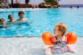 Cute happy little toddler girl, two school kid boys and father in the pool and having fun on family vacations in a hotel Royalty Free Stock Photo