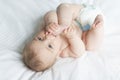 Cute happy 7 month baby girl in diaper lying and playing Royalty Free Stock Photo