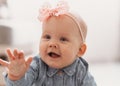 Cute happy 6 months baby girl with pink bow crawling indoor. Pretty smiling kid Royalty Free Stock Photo