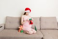 Cute happy pregnant woman in dress at home in santa hat. Mother to be with big belly, hands over tummy. Merry Christmas Royalty Free Stock Photo