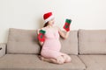 Cute happy pregnant woman in dress at home in santa hat. Mother to be with big belly, hands over tummy. Merry Christmas