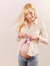 Cute happy pregnant woman expecting a baby girl with little pink