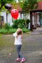 Cute happy preschool girl playing with ladybug balloon outdoors. Little child celebrating birthday. Royalty Free Stock Photo