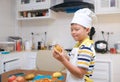 Cute happy smiling Asian boy child wearing chef hat and apron having fun preparing, cooking healthy Homemade Japanese Curry Rice