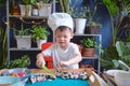 Cute happy smiling Asian little boy child wearing chef hat having fun preparing, cooking healthy Japanese food -  sushi roll at Royalty Free Stock Photo