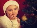 Cute happy smiling girl in fur santa claus hat near the Christmas holiday tree with toys looking. Closeup bright portrait Royalty Free Stock Photo