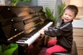 Cute happy smiling little Asian kid boy playing piano in living room, Preschool child having fun with learning to play music Royalty Free Stock Photo