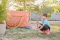 Little Asian kid having fun holding hammer, pretend to set up a camping tent in backyard at home