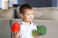 Cute happy smiling little boy holding raw vegetables broccoli and red pepper in his hands. Healthy food, diet, vegetarianism and v