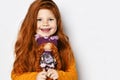 Cute happy smiling red-haired kid girl in orange sweatshirt holds small redhair doll her portrait in hands at face Royalty Free Stock Photo