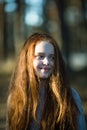 Cute happy teen girl with long bright red hair closeup portrait outdoors