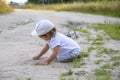 Cute happy toddler in a cap crawls on all fours along a country road in the sand on a sunny summer day Royalty Free Stock Photo