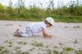 Cute happy toddler in a cap crawls on all fours along a country road in the sand on a sunny summer day Royalty Free Stock Photo