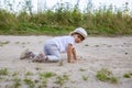 Cute happy toddler in a cap crawls on all fours along a country road in the sand on a sunny summer day Royalty Free Stock Photo