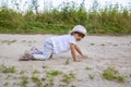 cute happy toddler in a cap crawls on all fours along a country road in the sand on a sunny summer day Royalty Free Stock Photo