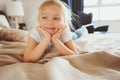 Cute happy toddler girl sitting on bed in pajama