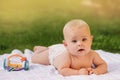 Cute happy toddler lying on a blanket on the grass outdoors in summer Royalty Free Stock Photo