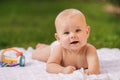 Cute happy toddler lying on a blanket on the grass outdoors in summer Royalty Free Stock Photo