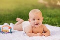 Cute happy toddler lying on a blanket on the grass outdoors in summer Royalty Free Stock Photo