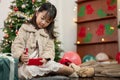 A cute and happy young Asian girl is opening a Christmas gift in the living room Royalty Free Stock Photo