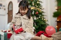 A cute and happy young Asian girl is opening a Christmas gift in the living room Royalty Free Stock Photo
