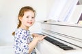 Cute healthy kid girl playing piano in living room or music school. Preschool child having fun with learning to play Royalty Free Stock Photo