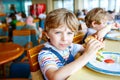 Cute healthy preschool boy eats hamburger sitting in school canteen Royalty Free Stock Photo