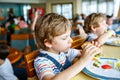 Cute healthy preschool kid boy eats hamburger sitting in school or nursery cafe. Happy child eating healthy organic and Royalty Free Stock Photo