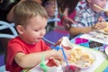 Cute healthy preschool kid boy eats sitting in school or nursery cafe. Happy child eating healthy organic and vegan food in restau