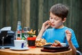 Cute healthy teenager boy eats hamburger and potato