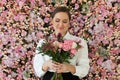 Cute healthy woman smiling and holding colorful pink color flower bouquet on floral spring or summer background, studio fashion Royalty Free Stock Photo