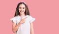 Cute hispanic child girl wearing casual white tshirt cheerful with a smile on face pointing with hand and finger up to the side Royalty Free Stock Photo