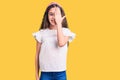 Cute hispanic child girl wearing casual white tshirt covering one eye with hand, confident smile on face and surprise emotion Royalty Free Stock Photo