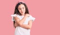 Cute hispanic child girl wearing casual white tshirt hugging oneself happy and positive, smiling confident Royalty Free Stock Photo