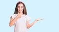 Cute hispanic child girl wearing casual white tshirt showing palm hand and doing ok gesture with thumbs up, smiling happy and Royalty Free Stock Photo