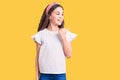 Cute hispanic child girl wearing casual white tshirt smiling with happy face looking and pointing to the side with thumb up Royalty Free Stock Photo